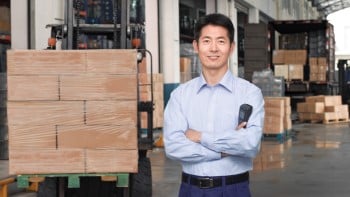 Warehouse manager with hand scanner in front of boxes