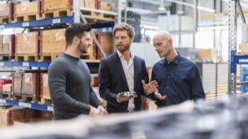 Businessmen in warehouse discussing technical part