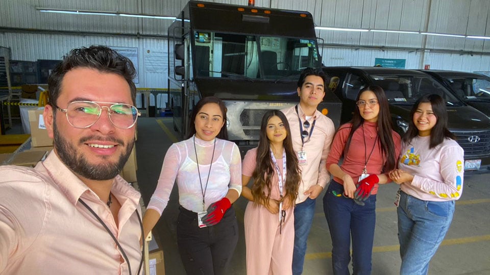 UPS employees standing together in warehouse smiling. 