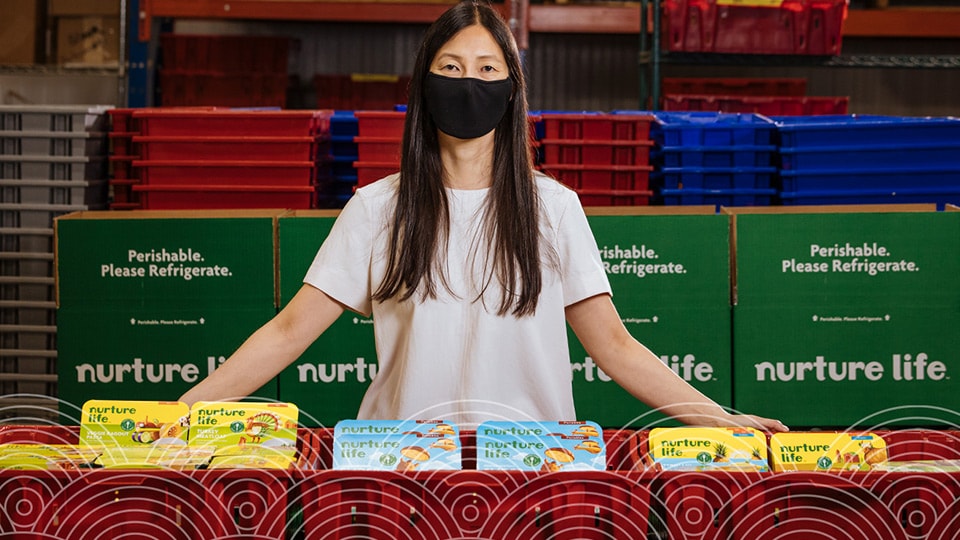 Jennier Chow in a mask sitting at a Nurture Life table