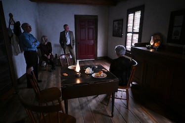 Photo of and visitors looking at exhibition room with person seated at tables