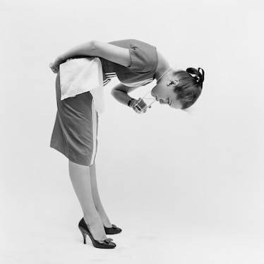 a woman bent over to drink a glass of water with her head upside down