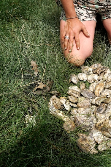 woman kneeling in front of oysters