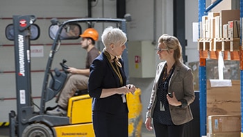 Two women discussing specialized shipping services in warehouse