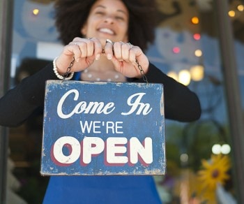 Small business owner holding open sign