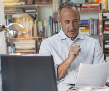 Business casual man in home office holding a document and pen