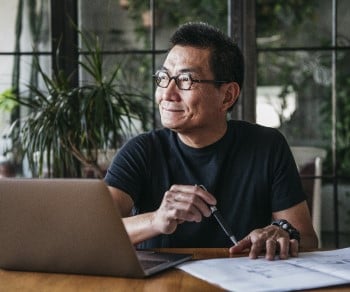 Man with laptop thinking in office