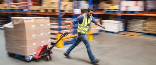 Warehouse worker pulling shrink-wrapped pallet