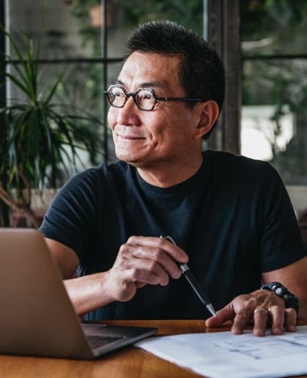 Man with laptop thinking in office