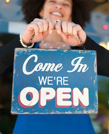 Small business owner holding open sign