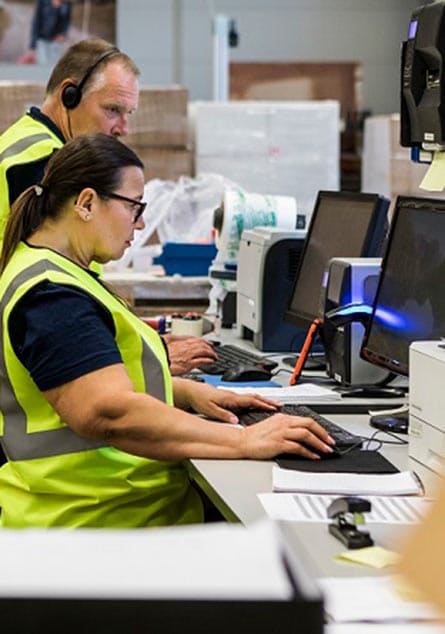 woman and man in yellow vests working on computers