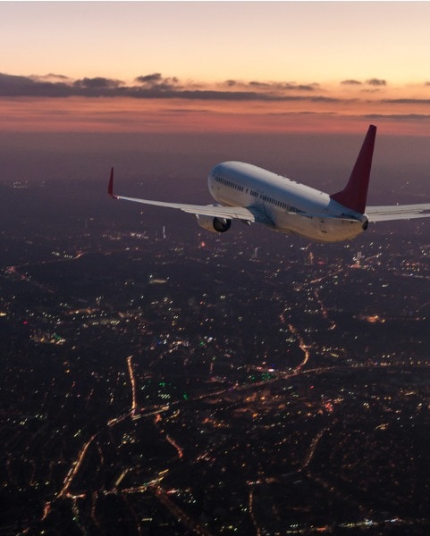 plane flying in sky at sunset