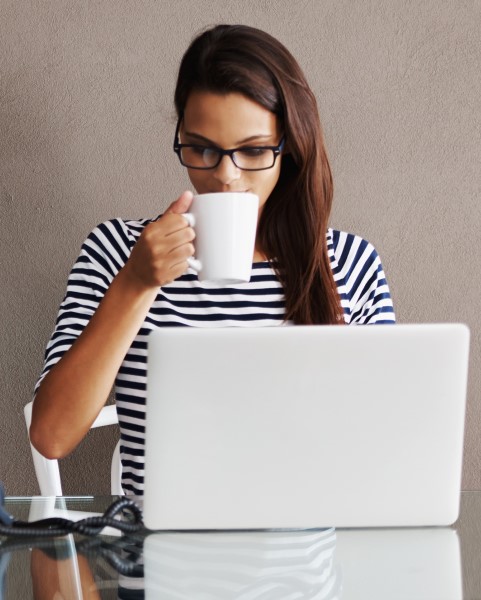 Woman sipping coffee and watching a webinar on her computer