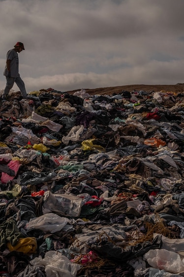 two people walk around a massive mountain of clothing