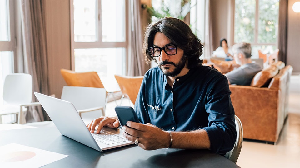 Man checking both laptop and mobile device.