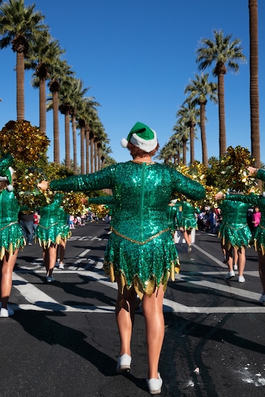 Picture of view from behind at women dressed in emerald-green short dresses and hats.