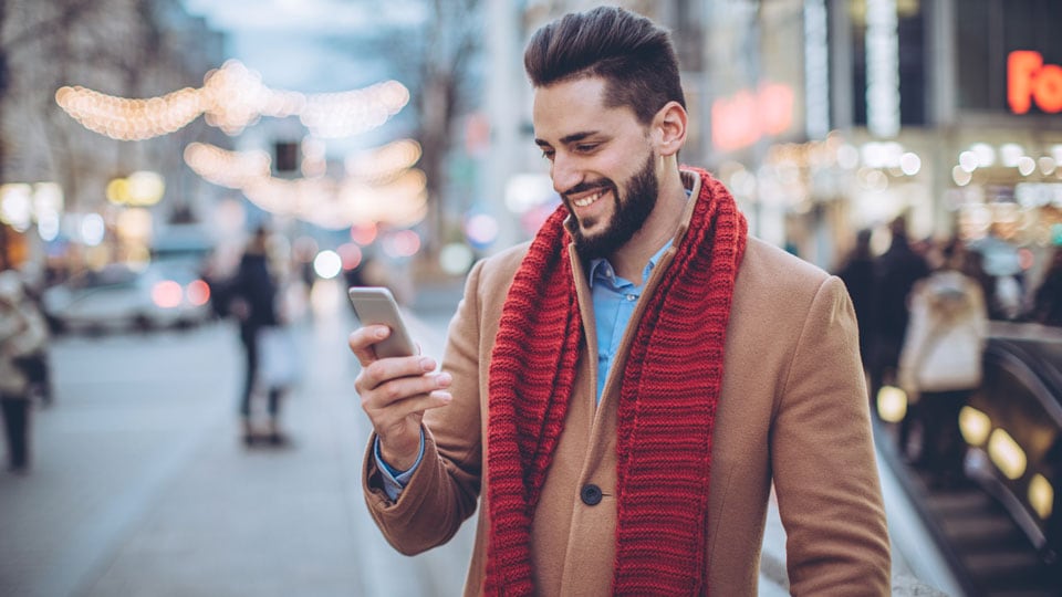 Man standing outside in winter looking at phone.