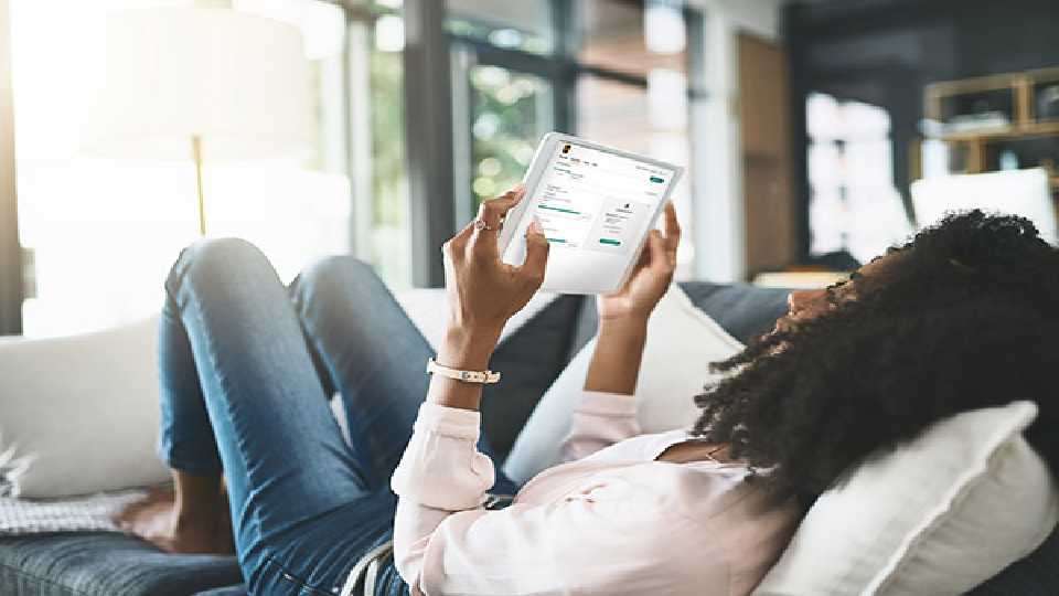 Woman laying on couch looking at ipad