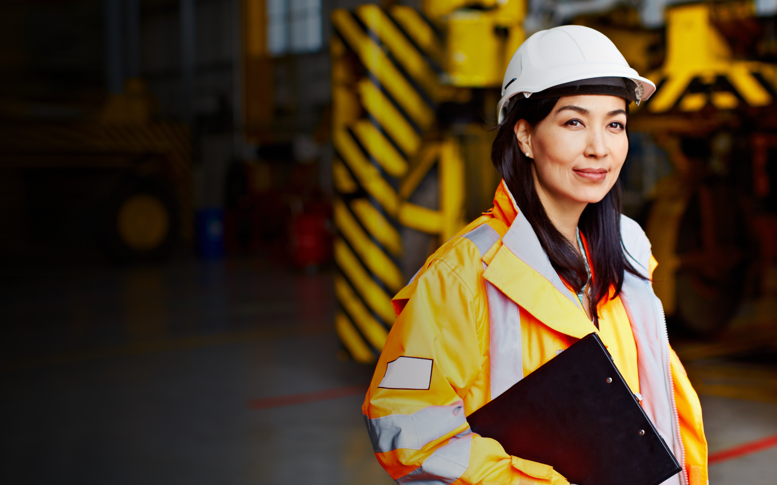 woman in workwear standing in a large industrial building